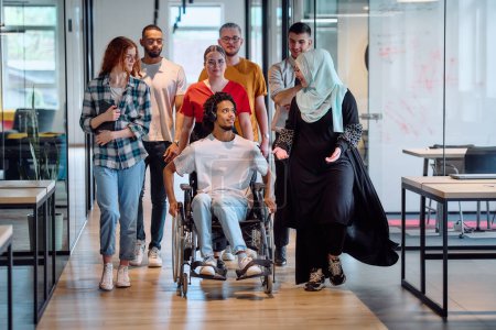 Eine vielfältige Gruppe junger Geschäftsleute trifft sich in einem modernen, gläsernen Büro für Start-ups, das Inklusivität mit einer Person im Rollstuhl, einem jungen Afroamerikaner und einem Hijab bietet.