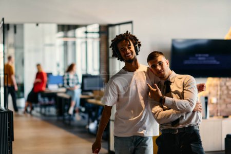 Téléchargez les photos : Un groupe de collègues, dont un homme d'affaires afro-américain et un jeune leader en chemise et cravate, posent ensemble dans un bureau moderne de centre de coworking, représentant un mélange dynamique de - en image libre de droit