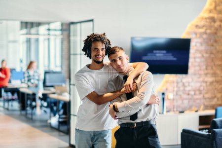 Eine Gruppe von Kollegen, darunter ein afroamerikanischer Geschäftsmann und ein junger Führer in Hemd und Krawatte, posieren gemeinsam in einem modernen Coworking Center-Büro und repräsentieren eine dynamische Mischung aus