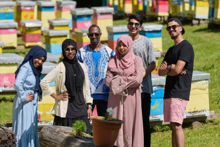 Foto de Un grupo diverso de jóvenes amigos y empresarios exploran pequeños negocios de producción de miel en el entorno natural del campo - Imagen libre de derechos