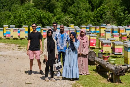 Téléchargez les photos : Un groupe diversifié de jeunes amis et entrepreneurs explore de petites entreprises de production de miel dans le cadre naturel de la campagne - en image libre de droit