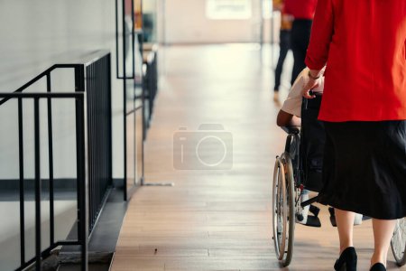 Téléchargez les photos : Une femme d'affaires aide son collègue en fauteuil roulant dans les couloirs élégants d'un bureau de démarrage moderne, incarnant l'inclusivité et le travail d'équipe. - en image libre de droit