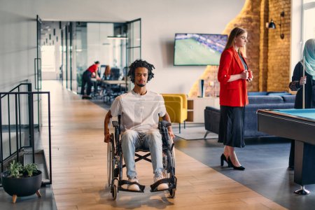 Photo for An African-American young entrepreneur in a wheelchair is surrounded by his business colleagues in a modern office setting, embodying diversity and collaboration in the workplace. - Royalty Free Image