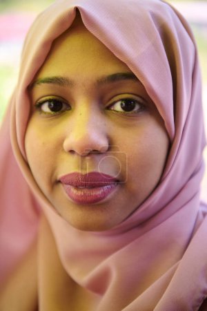 Téléchargez les photos : Une fille du Moyen-Orient portant un hijab, avec un sourire éclatant et un foulard rose, capturée dans un portrait en gros plan exsudant joie et positivité. - en image libre de droit