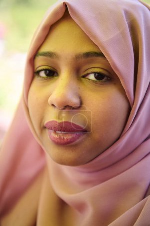Téléchargez les photos : Une fille du Moyen-Orient portant un hijab, avec un sourire éclatant et un foulard rose, capturée dans un portrait en gros plan exsudant joie et positivité. - en image libre de droit