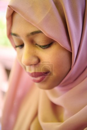 Foto de Una chica de Oriente Medio que lleva un hijab, con una sonrisa brillante y un pañuelo rosa en la cabeza, capturado en un retrato de cerca que exuda alegría y positividad. - Imagen libre de derechos