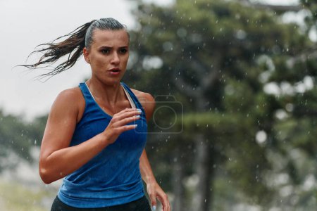 Foto de Lluvia o brillo, una maratonista dedicada a través de su carrera de entrenamiento, sus ojos puestos en la línea de meta. - Imagen libre de derechos