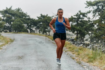 Regen oder Sonnenschein, eine engagierte Marathonläuferin fährt durch ihren Trainingslauf, die Augen auf die Ziellinie gerichtet. 