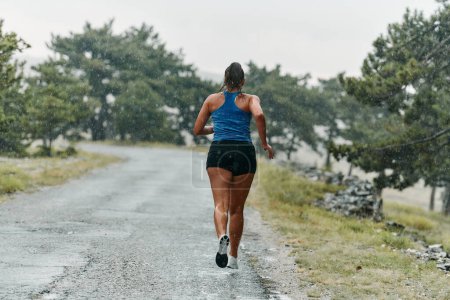 Téléchargez les photos : Pluie ou brillance, une marathonienne dévouée à travers sa course d'entraînement, les yeux fixés sur la ligne d'arrivée. - en image libre de droit