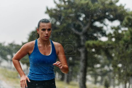 Regen oder Sonnenschein, eine engagierte Marathonläuferin fährt durch ihren Trainingslauf, die Augen auf die Ziellinie gerichtet. 