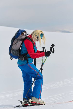 Un esquiador determinado escala un pico cubierto de nieve en los Alpes, llevando equipo de backcountry para un descenso épico