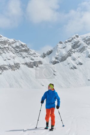 Photo for A lone skier braves the elements on a perilous climb to the top of an alpine peak. - Royalty Free Image