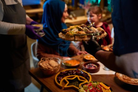 In einer herzerwärmenden Szene serviert ein professioneller Koch einer europäischen muslimischen Familie ihr Iftar-Essen während des heiligen Monats Ramadan und verkörpert damit kulturelle Einheit und kulinarische Gastfreundschaft in einem Moment gemeinsamer