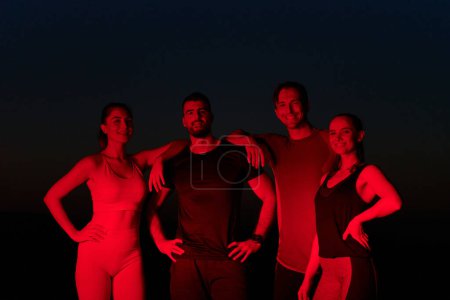 En las últimas horas de la noche, un diverso grupo de atletas exhaustos encuentran consuelo bajo un resplandor rojo, reflexionando sobre su viaje maratónico de un día y celebrando la camaradería en medio de la fatiga..