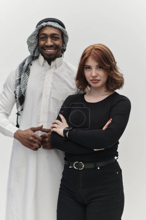 Entrepreneur musulman et une jeune fille aux cheveux roux contemporaine posent ensemble sur un fond blanc propre, incarnant la confiance, la diversité et un esprit d'entreprise dynamique dans leur