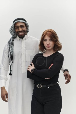 Entrepreneur musulman et une jeune fille aux cheveux roux contemporaine posent ensemble sur un fond blanc propre, incarnant la confiance, la diversité et un esprit d'entreprise dynamique dans leur