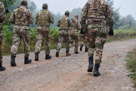 Une unité militaire d'élite, dirigée par un major, parade en toute confiance dans une forêt dense, faisant preuve de précision, de discipline et d'état de préparation pour les opérations à haut risque. 