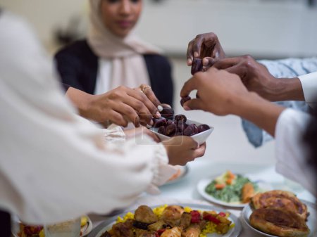 Una mujer en un hiyab extiende una bandeja de dátiles a su diversa familia, creando una escena de unidad y alegría mientras se reúnen para romper su ayuno durante el mes santo del Ramadán, simbolizando el