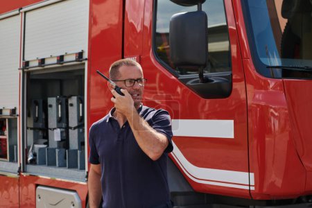 Un pompier dévoué, capturé dans un moment de communication, se tient devant un camion de pompiers moderne, montrant l'intégration transparente de la technologie dans l'intervention d'urgence. 
