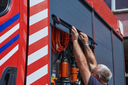 Un bombero dedicado a preparar un camión de bomberos moderno para su despliegue en áreas afectadas por incendios peligrosos, demostrando disposición y compromiso con la respuesta de emergencia. 