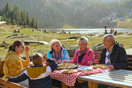 Eine Familie im Urlaub in den Bergen genießt die Freuden eines gesunden Lebens, genießt traditionelle Torten, während sie von der atemberaubenden Schönheit der Natur umgeben ist, pflegt Familienbande und umarmt die Natur.