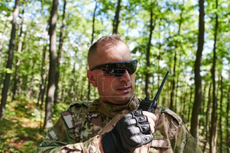 Ein Militärmajor setzt während einer taktischen Operation ein Motorola-Funkgerät für die nahtlose Kommunikation mit seinen Soldatenkollegen ein und demonstriert damit Professionalität und strategische Koordination. 