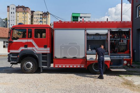 Ein engagierter Feuerwehrmann bereitet ein modernes Feuerwehrfahrzeug für den Einsatz in gefährlichen Brandgebieten vor und demonstriert damit Einsatzbereitschaft und Engagement im Katastrophenfall. 