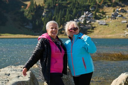 Femmes âgées randonneurs debout sur la montagne profitant d'une journée de trekking - Souriantes touristes d'escalade profitant de vacances et d'un mode de vie sain - Liberté, succès concept sportif. 
