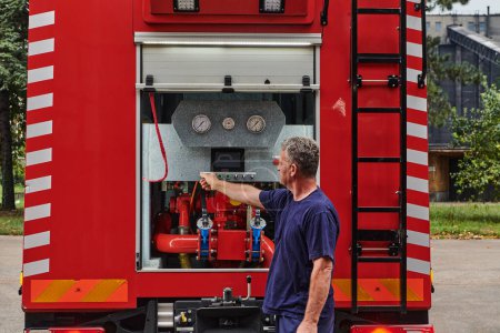 Un pompier dévoué prépare un camion de pompiers moderne en vue d'un déploiement dans des zones touchées par un incendie dangereux, démontrant ainsi son état de préparation et son engagement à intervenir en cas d'urgence. 
