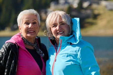 Femmes âgées randonneurs debout sur la montagne profitant d'une journée de trekking - Souriantes touristes d'escalade profitant de vacances et d'un mode de vie sain - Liberté, succès concept sportif. 