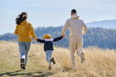 Une famille moderne, avec leur fils, se réjouit de la joie d'une journée boueuse dans la nature, courir et jouer ensemble, résumant la beauté d'un mode de vie sain et actif.