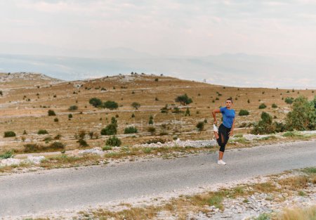 A determined female athlete stretches her muscles after a strenuous run through rugged mountain terrain, surrounded by breathtaking rocky landscapes. 