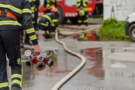 Photo for In a dynamic display of synchronized teamwork, firefighters hustle to carry, connect, and deploy firefighting hoses with precision, showcasing their intensive training and readiness for challenging - Royalty Free Image