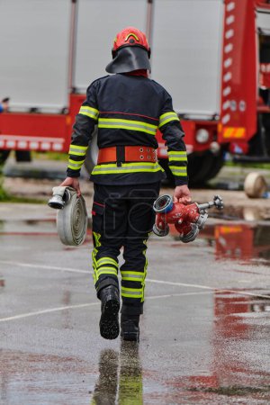 In einem dynamischen Schauspiel synchronisierter Teamarbeit versuchen Feuerwehrleute, Feuerwehrschläuche präzise zu tragen, zu verbinden und einzusetzen und zeigen dabei ihre intensive Ausbildung und Bereitschaft für anspruchsvolle Aufgaben.