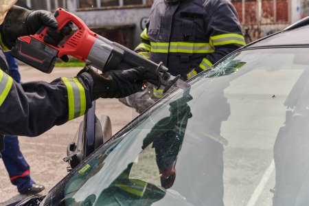 Une équipe dévouée de pompiers professionnels utilise des outils spécialisés pour couper et percer l'épave du véhicule, mettant en valeur leur collaboration qualifiée et leur réponse rapide pour sauver des personnes.