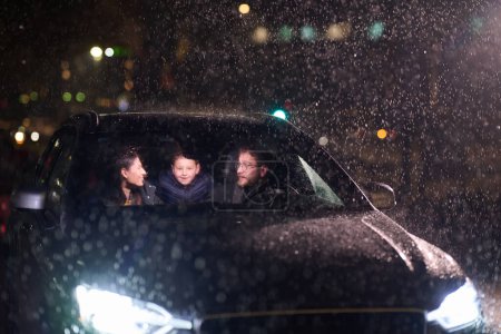 Au milieu d'un voyage nocturne, une famille heureuse profite de moments ludiques à l'intérieur d'une voiture alors qu'ils voyagent par temps pluvieux, illuminés par la lueur des phares, des rires et des liens.
