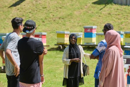 Un groupe diversifié de jeunes amis et entrepreneurs explore de petites entreprises de production de miel dans le cadre naturel de la campagne