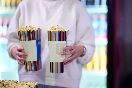 Ein Verkäufer steht vor dem Kino und hält frisch geknalltes Popcorn in der Hand, um es den Kinobesuchern zu verkaufen, bevor sie das Theater betreten..