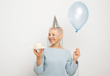 Téléchargez les photos : People, party, aging and maturity concept. Beauitful elderly female wearing conical hat celebrating birthday - en image libre de droit