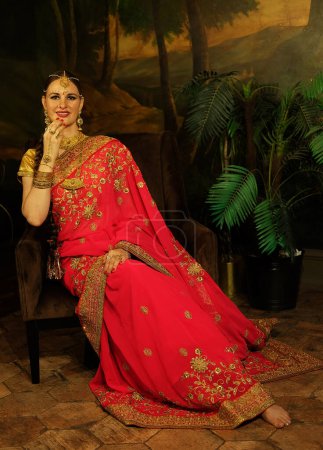 Foto de Retrato de una hermosa hembra india. Joven mujer hindú modelo Kundan joyas. Traje indio tradicional saree rojo. - Imagen libre de derechos