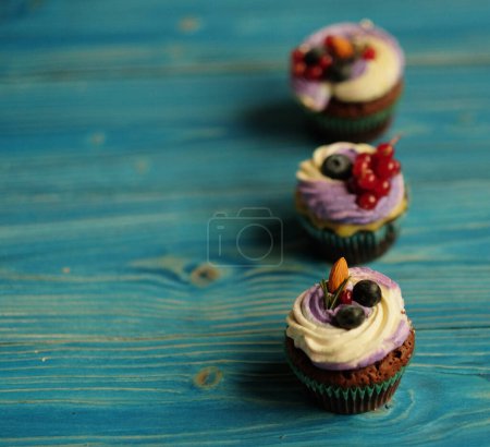 Photo for Cupcakes with fresh berries, homemade cakes over blue wooden table, close up - Royalty Free Image