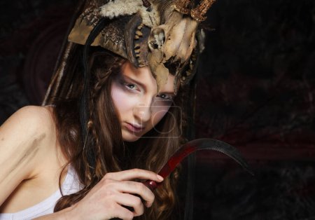 Téléchargez les photos : Jeune femme au maquillage agressif tenant une faucille. Halloween. Fête costumée. - en image libre de droit
