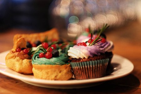 Téléchargez les photos : Gâteaux frais sur une assiette - cupcakes et éclairs, fermer - en image libre de droit