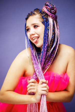 Foto de Mujer encantadora joven con peinado dreadlocks y maquillaje creativo en estilo muñeca sobre fondo púrpura. - Imagen libre de derechos