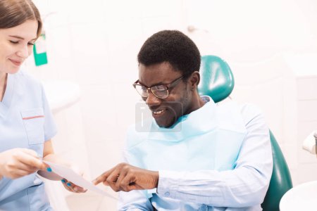 Foto de Doctora dentista joven mostrando el resultado del tratamiento dental demostrando la inyección de rayos X de los dientes durante el chequeo en el gabinete estomatológico moderno. - Imagen libre de derechos