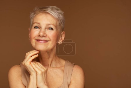 Photo for Beauty portrait of mature woman smiling with hand on face. Closeup face of happy senior woman feeling fresh after anti-aging treatment. Smiling beauty looking at camera with perfect skin. - Royalty Free Image