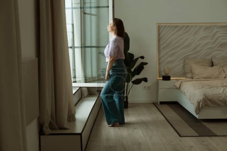 Téléchargez les photos : Woman Standing By Bedroom Window And Opening Curtains. Lifestyle concept. - en image libre de droit