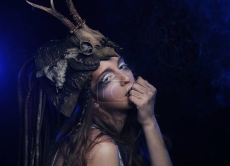 Téléchargez les photos : Gros plan portrait de jeune femme avec un maquillage lumineux, des tresses et un crâne sur la tête, posant sur fond sombre fête, carnaval, Halloween. - en image libre de droit
