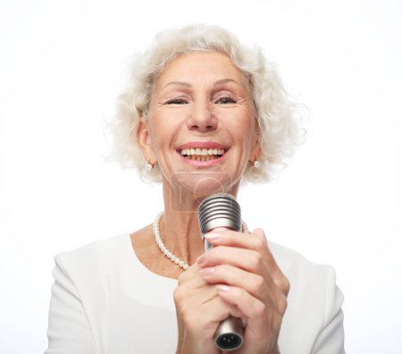 Foto de Retrato de la encantadora abuela moderna sostiene el micrófono sobre fondo blanco - Imagen libre de derechos