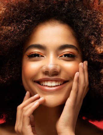 Téléchargez les photos : Style de vie, émotion et concept de personnes : Jeune belle femme afro-américaine aux cheveux afro souriants et heureux. Gros plan Portrait sur fond rouge. - en image libre de droit